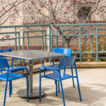 Maglin Foro tables and chairs painted blue and silver at CSUSM patio surrounded by lush gardens