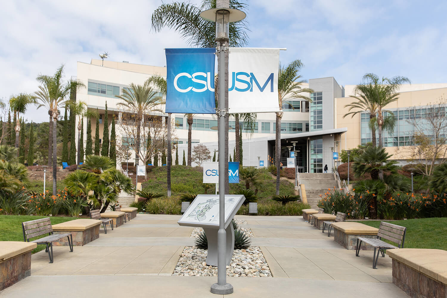 CSUSM flags hang over the entranceway to CSUSM University in California with Maglin Iconic benches