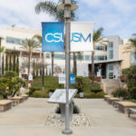 CSUSM flags hang over the entranceway to CSUSM University in California with Maglin Iconic benches