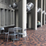 Foro tables and seating next to concrete pillars and interlocking brick