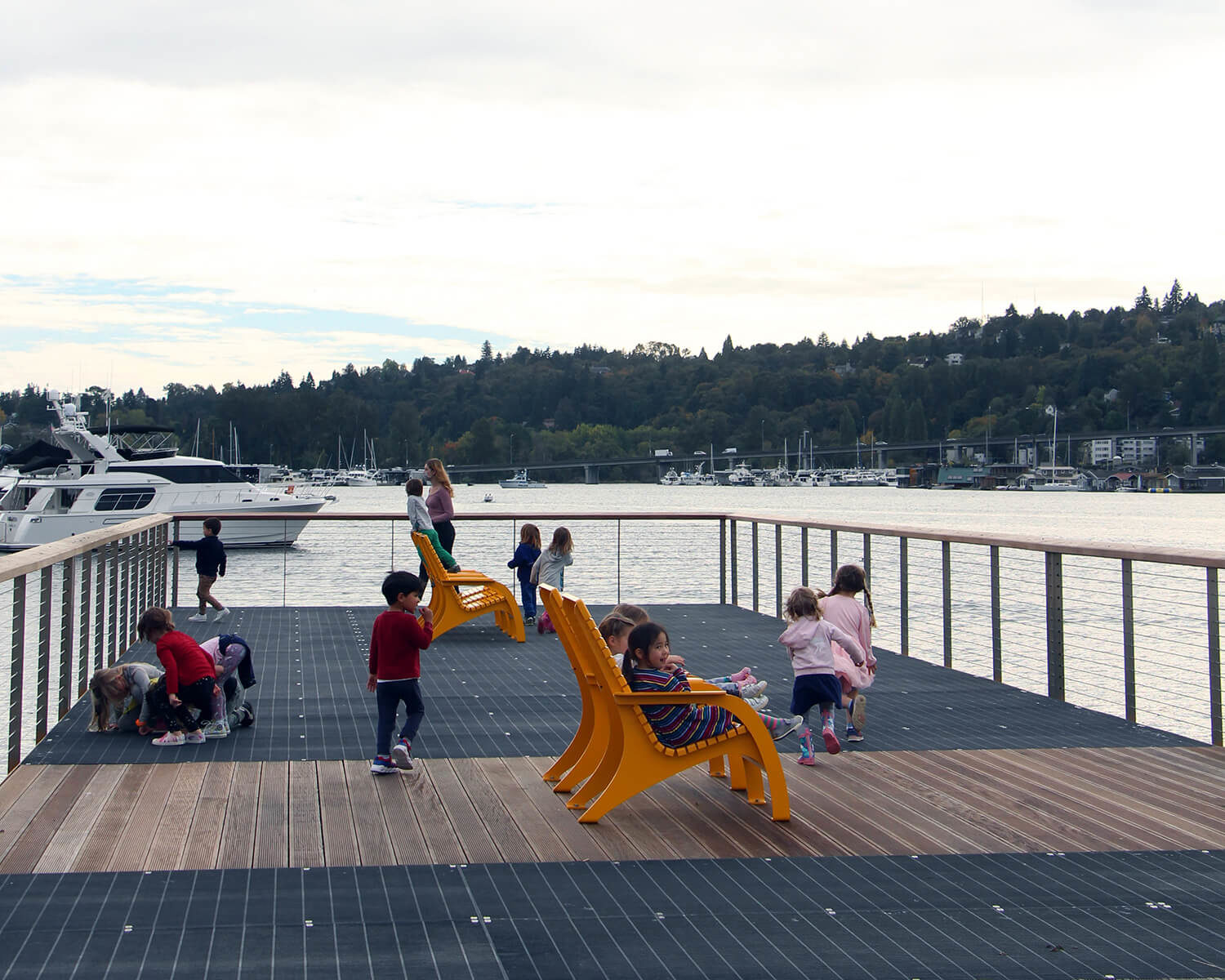 Children playing on dock with bright yellow Maglin 720 chairs overlooking water