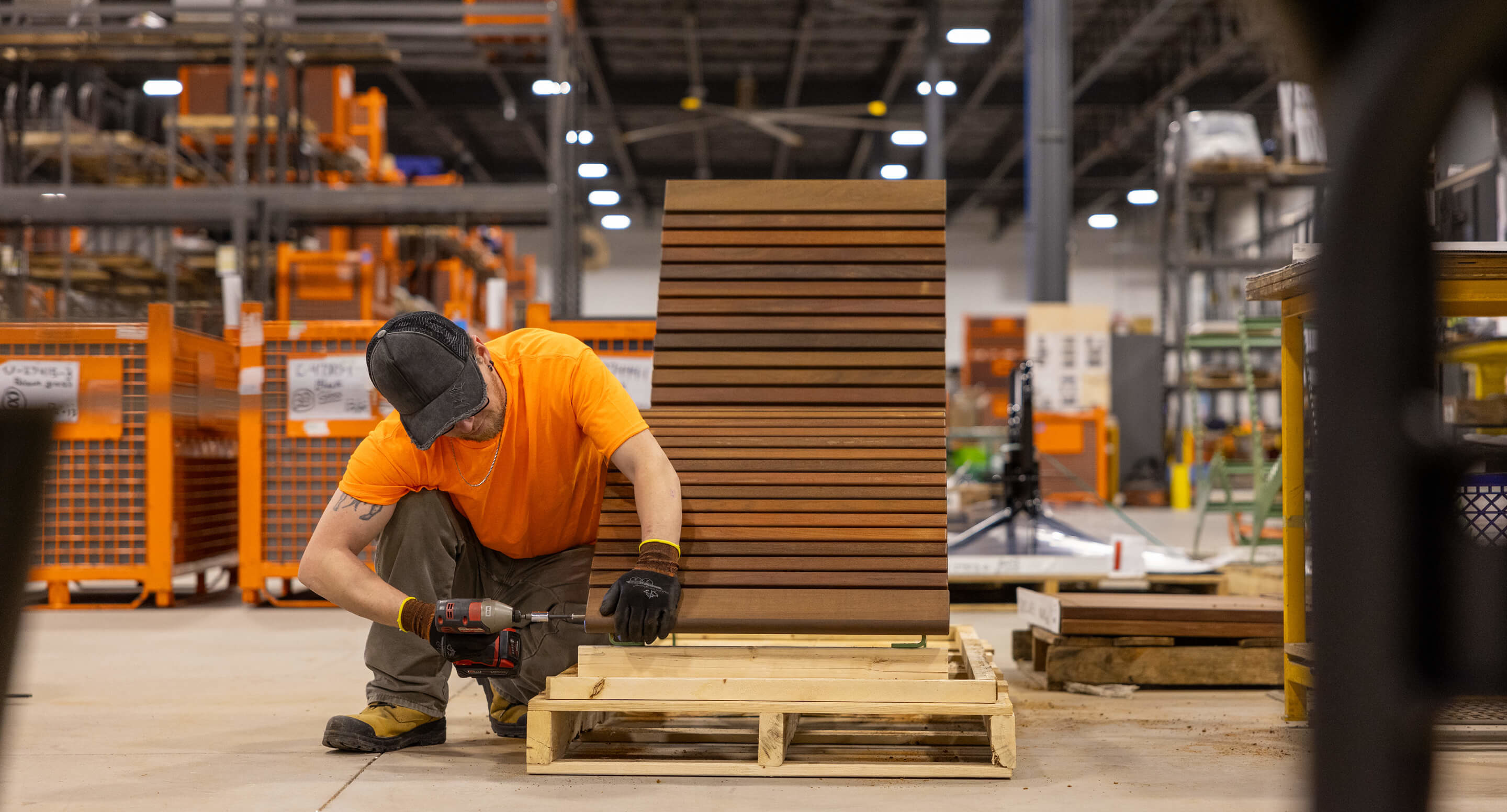 720-chaise-lounge-assembly-maglin-hq A Maglin employee wearing an orange t-shirt drills and assembles a 720 lounge chair in the warehouse.