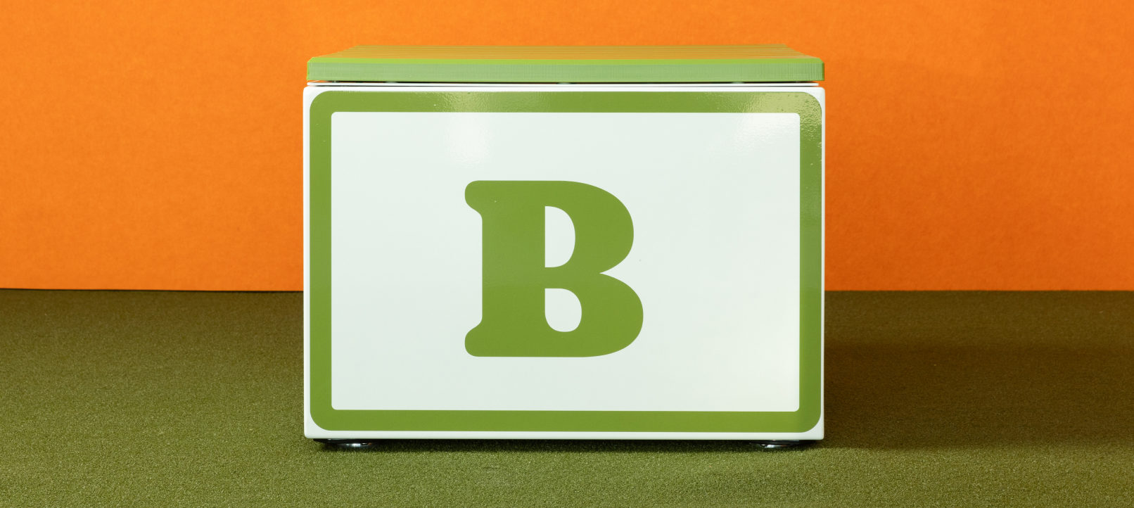 A large white block with a green letter 