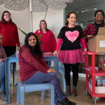 Maglin employees pose for a photo on Valentine's Day! Sarah wears a black t-shirt with a pink heart and Edgar has a tray of Valentine's Day goodies.