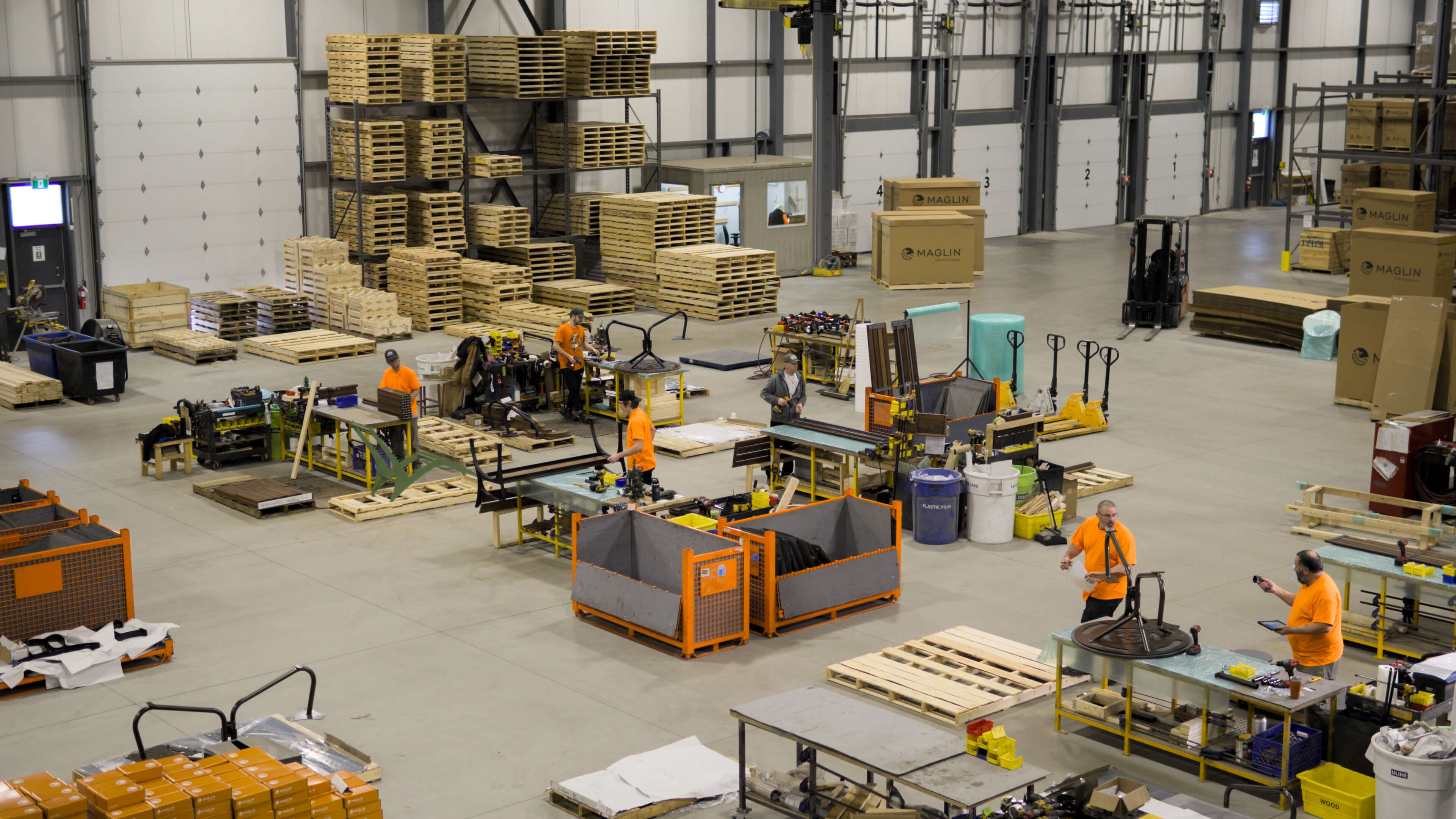 An image of Maglin employees assembling furniture taken from the mezzanine above at Maglin headquarters.
