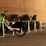 Row of white Iconic bike racks with bicycle locked against building