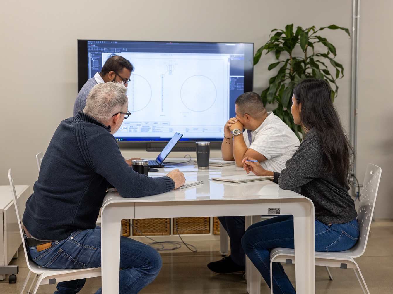 Maglin team working in office with big screen and laptop on ALUM table
