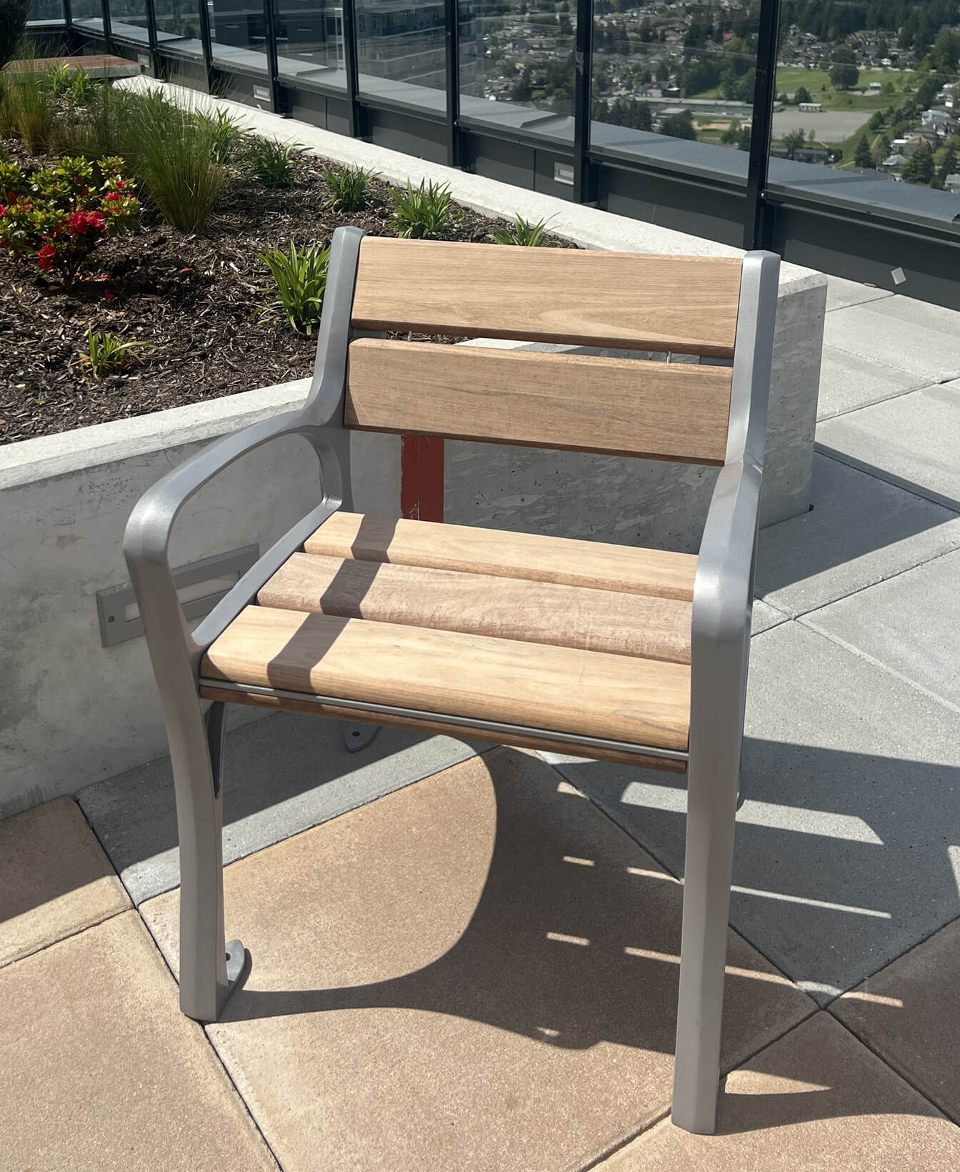 La Chaise 870, aux accents de bois et de métal, est installée sur un toit-terrasse carrelé, à côté d'un jardin surélevé rempli de plantes et de fleurs.