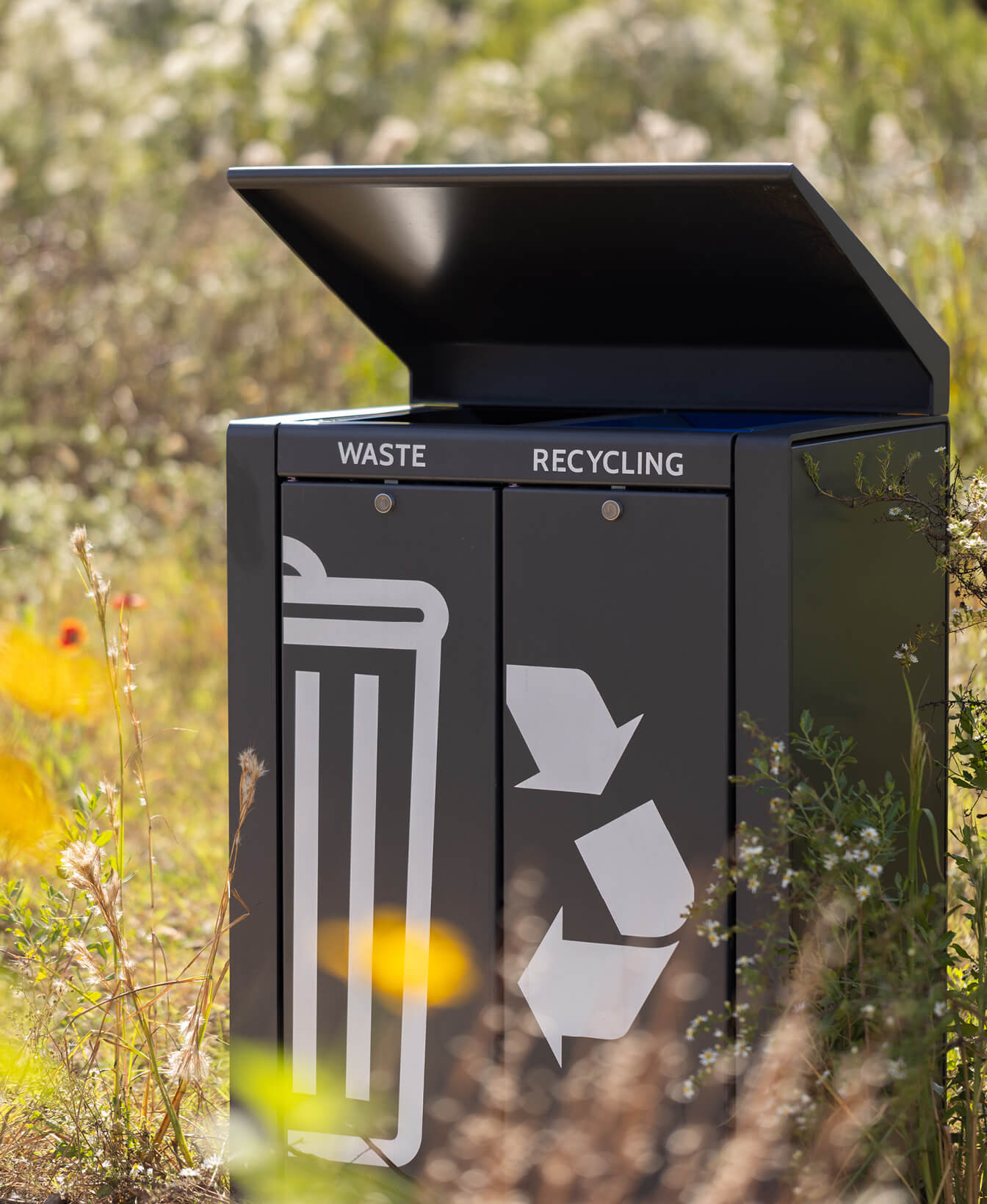 Le lexique Contenant de recyclage, qui comporte des étiquettes et des icônes claires, est placé à l'extérieur, sur une pelouse ensoleillée.