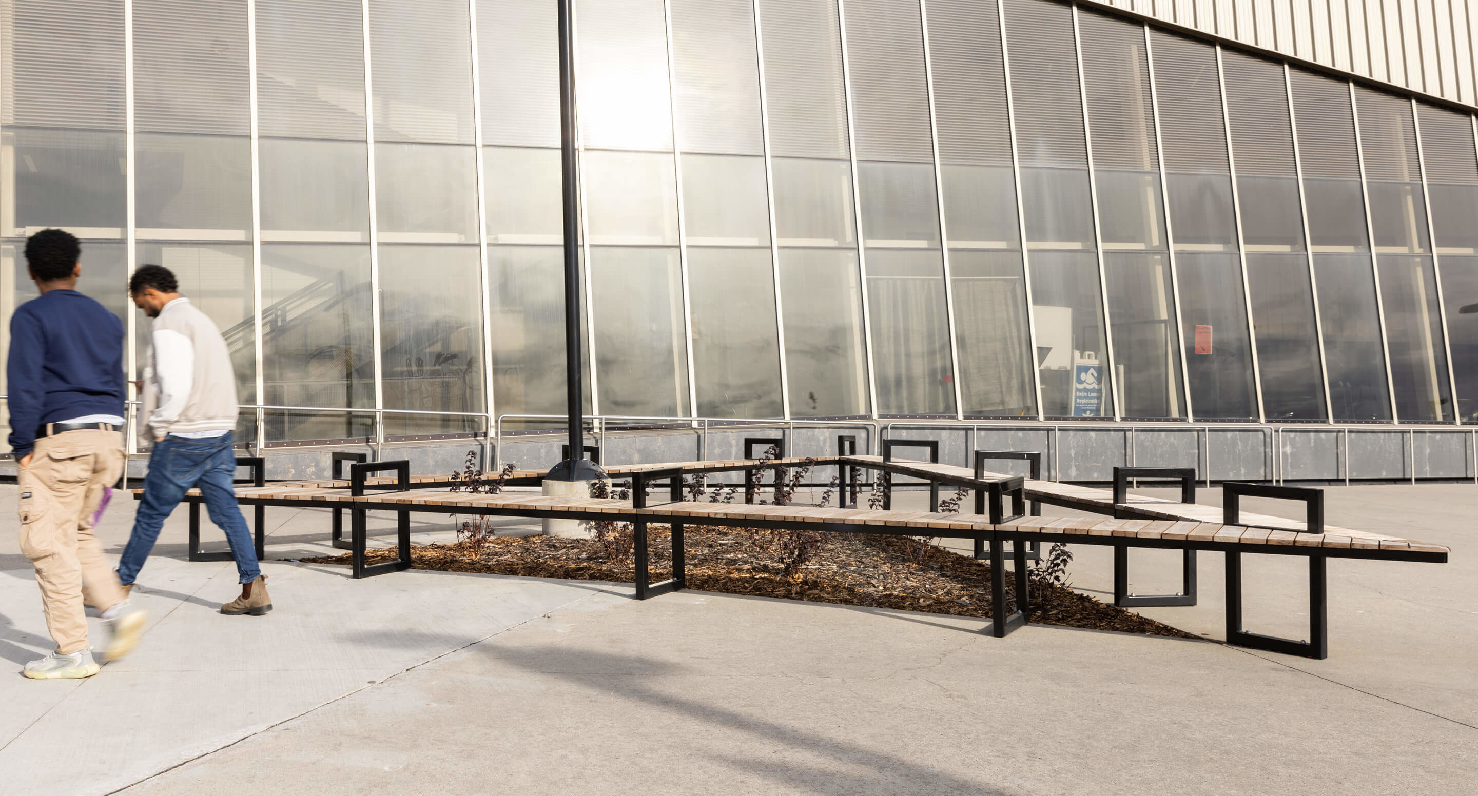 Students walking past modular Ogden bench seating with mitered corners around plantings