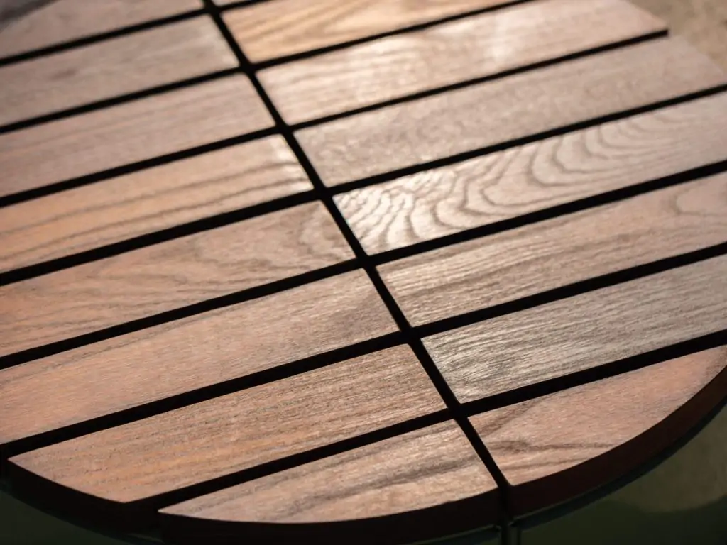 Close-up of a round wooden table with evenly spaced slats and visible wood grain.