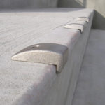 Close-up of a concrete ledge with several evenly spaced metal skate deterrents installed along the edge.
