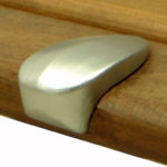 A silver, rounded metal pull handle is attached to the edge of a wooden drawer or cabinet.