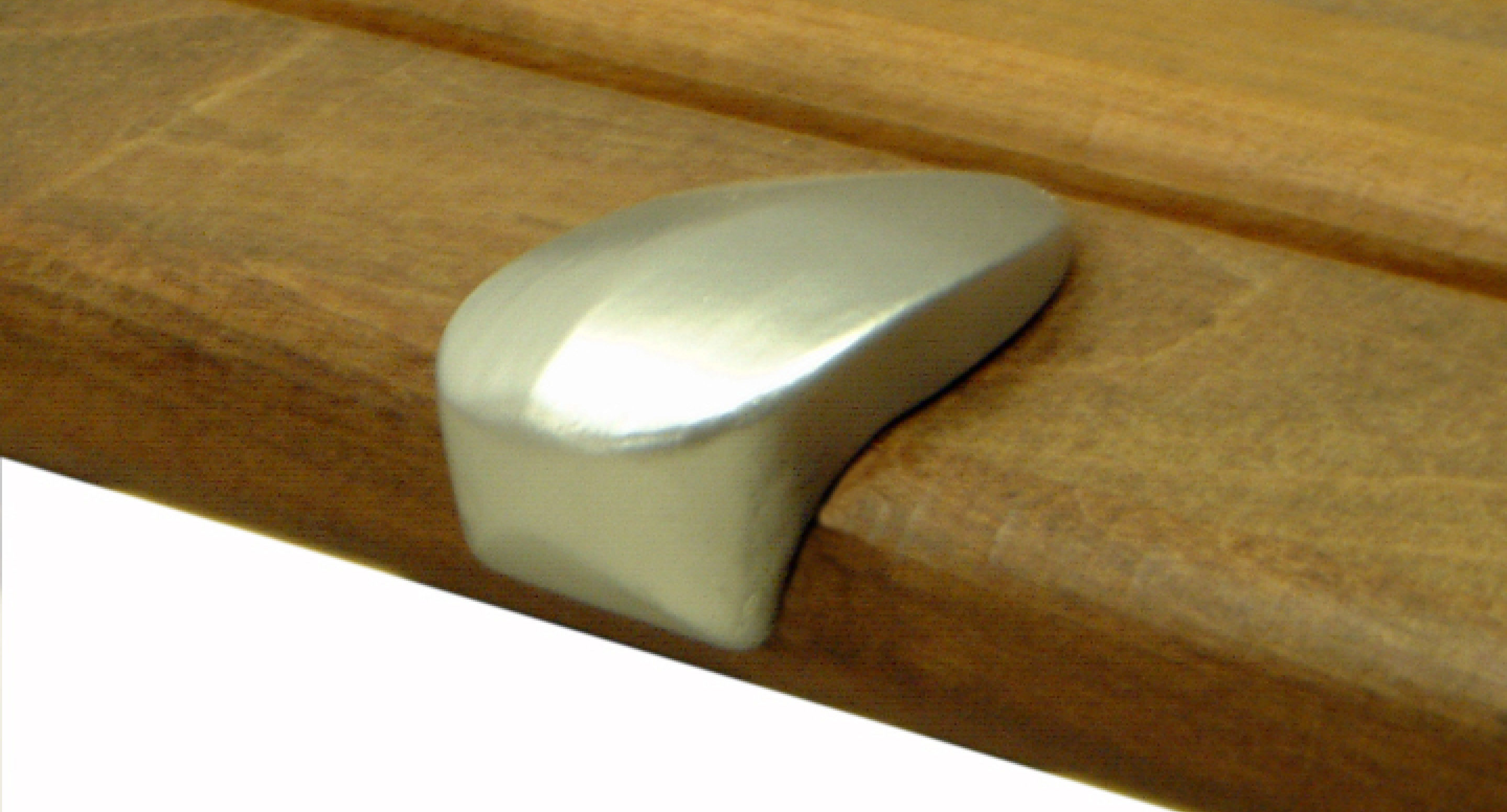 maglin_mbe-0100-bench-skate-deterrent-2 A silver, rounded metal pull handle is attached to the edge of a wooden drawer or cabinet.