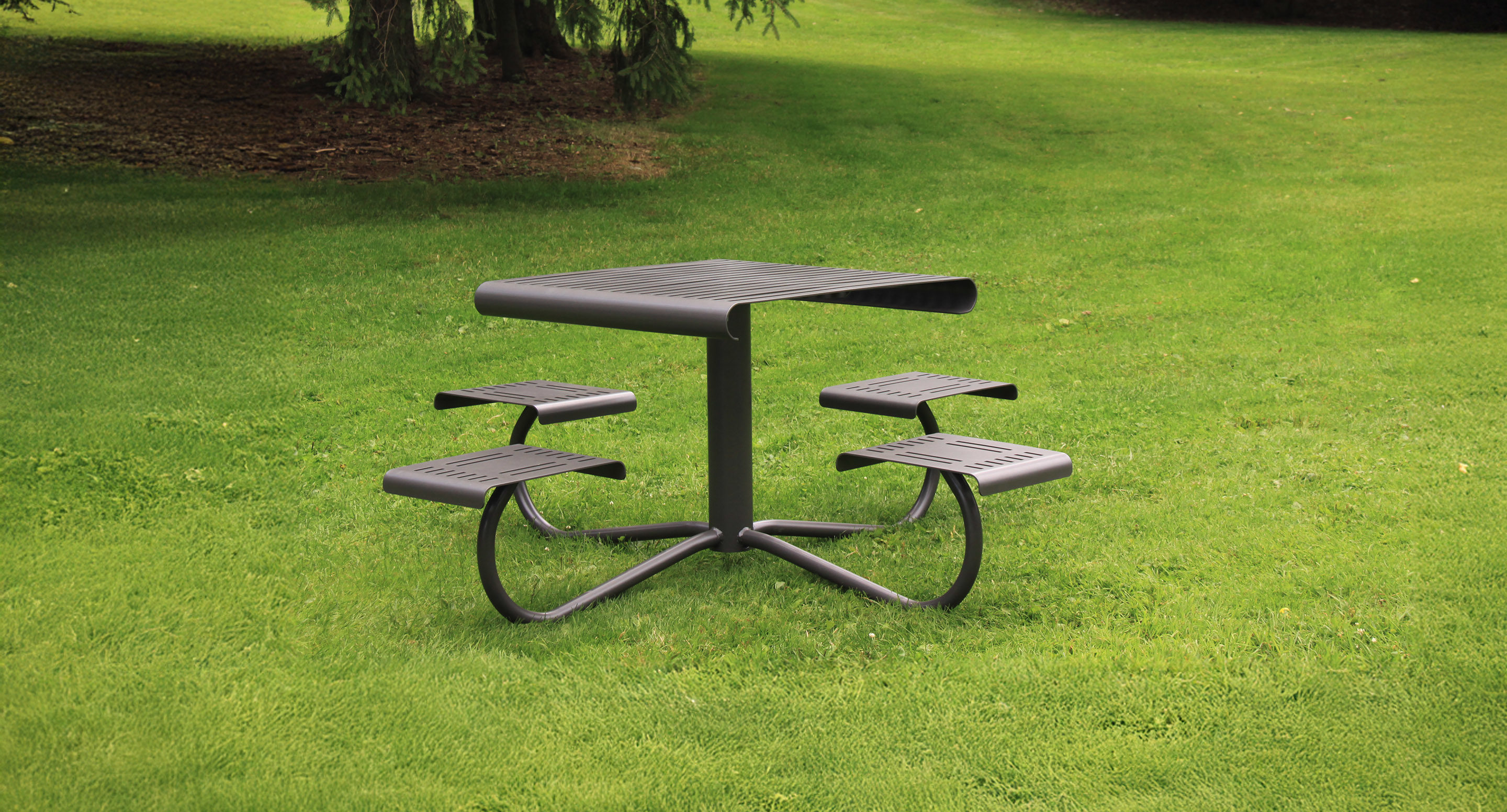 Une table de pique-nique moderne en métal avec quatre sièges est posée sur la pelouse verte d'un parc.