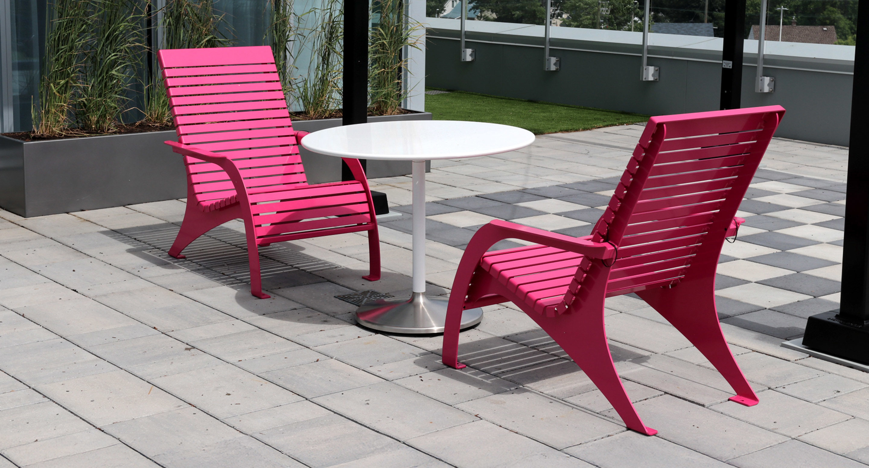 maglin_mtb-1800-battery-tables-1 Deux chaises roses à barreaux et une table ronde blanche sont placées sur un patio extérieur carrelé.