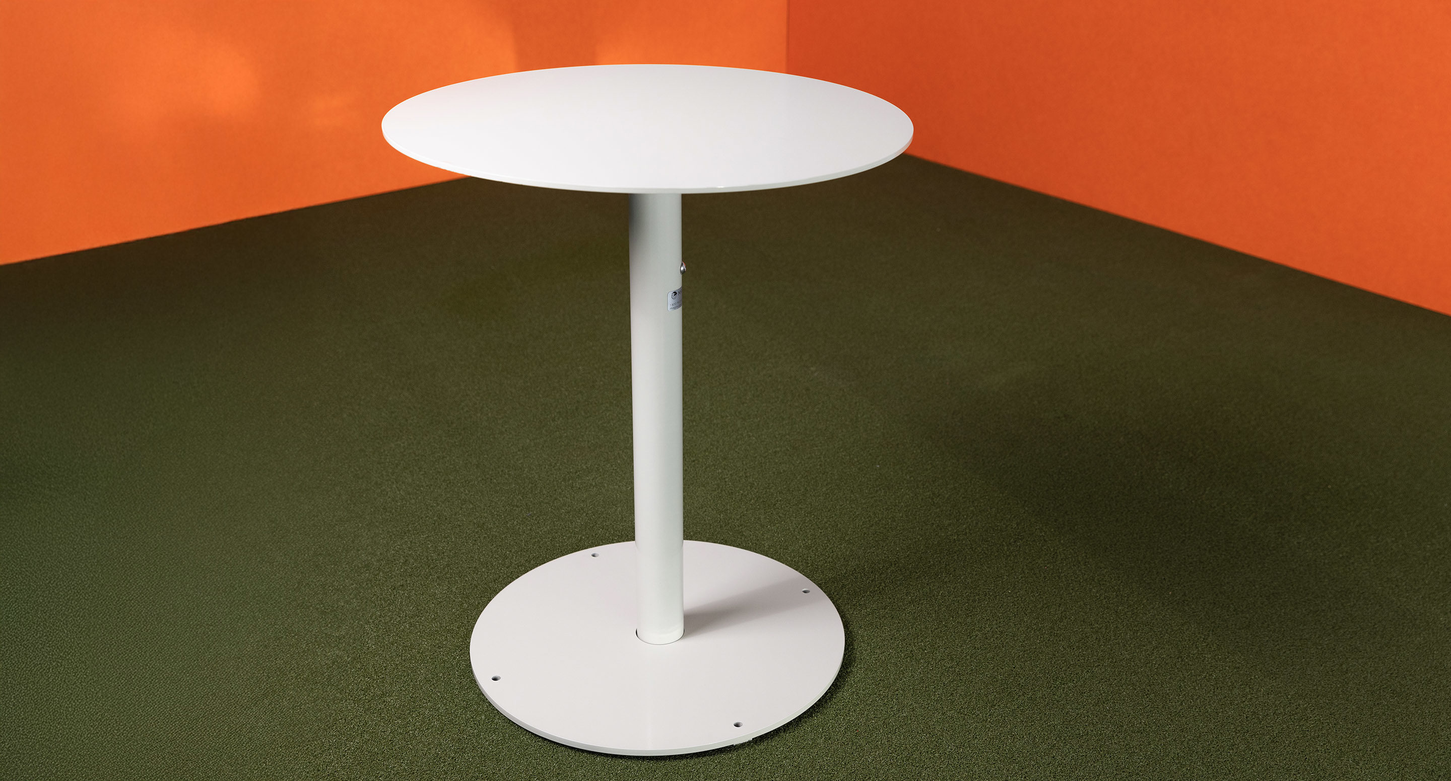 maglin_mtb-1900-ogden-cafe-tables-2 A round, white pedestal table stands on a green floor against orange walls.