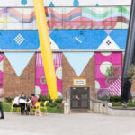 Wide view of movable seating at OCAD University’s Butterfield Park, with yellow Aries Café Chairs and Battery Tables under the iconic Sharp Centre for Design.