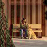 Un homme est assis sur un banc en bois à côté d'un golden retriever, touchant doucement le visage du chien, avec des arbres au premier plan et un mur en lattes derrière eux - une scène accueillante qui mérite d'être récompensée par un prix A+.