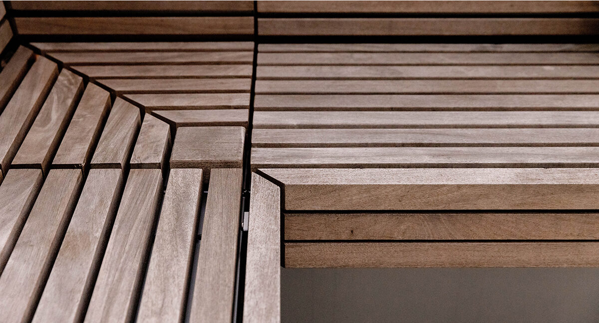 Close-up of intersecting wooden slats forming geometric patterns on a Pixel Collection bench at Link Apartments along Mint Street in Charlotte NC, with visible lines and angles.