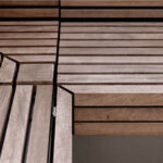 Close-up of intersecting wooden slats forming geometric patterns on a Pixel Collection bench at Link Apartments along Mint Street in Charlotte NC, with visible lines and angles.