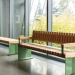 Deux bancs à lattes en bois, dotés d'une structure métallique vert clair, placés près d'une baie vitrée, arborant le label « Sélection de la rédaction d'AN ».