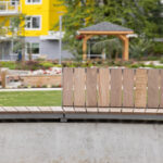 Un banc en lattes de bois installé contre un mur en béton dans un parc.