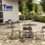 Outdoor patio seating with metal tables and chairs outside Two Brookline Place in Brookline, MA.